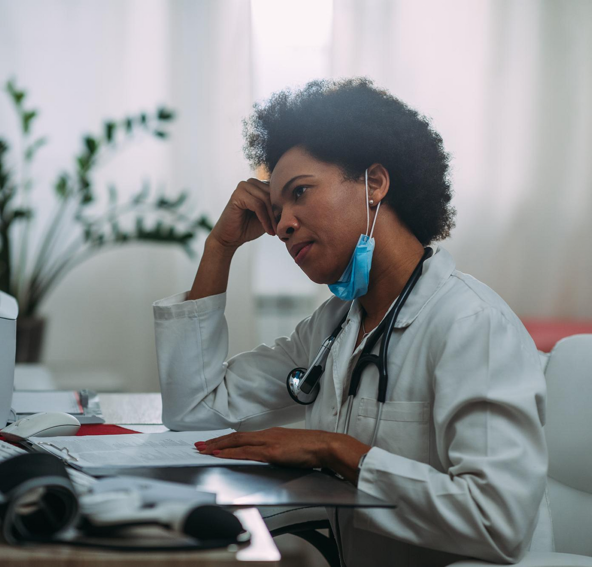 Healthcare worker holding her head at a charting workstation at night